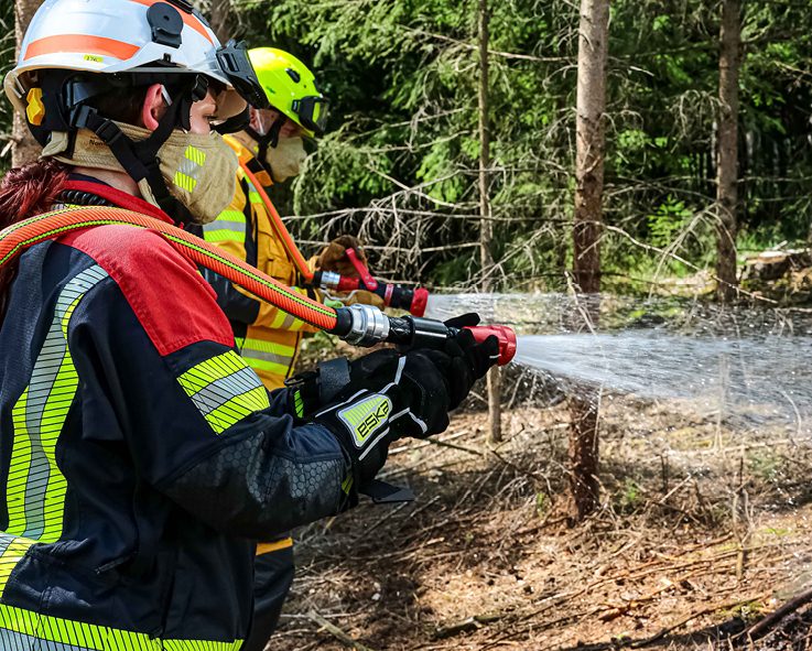 Feuerwehr Löscheinsatz am Waldrand mit Waldbrandschläuchen und Waldbrandstrahlrohren